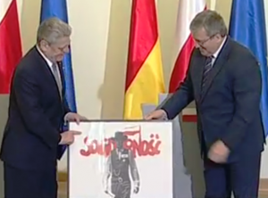 Der polnische Präsident Bronislaw Komorowski (rechts) schenkt Bundespräsident Joachim Gauck ein Wahlplakat der Solidarnosc aus dem Wendejahr 1989. 